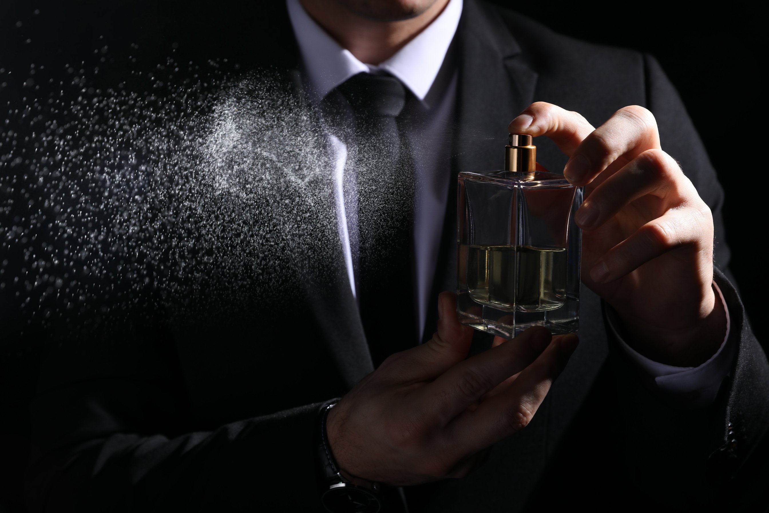 Man Spraying Luxury Perfume on Black Background, Closeup